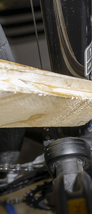 Photograph of wood shims about to be inserted behind Shimano Deore 3 speed front derailleur during cable tensioning process.